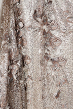 The image is a close-up view of a fabric with a floral pattern, featuring a mix of gold and brown colors. The fabric appears to be made of a shiny, sequined material, giving it a luxurious and elegant appearance.