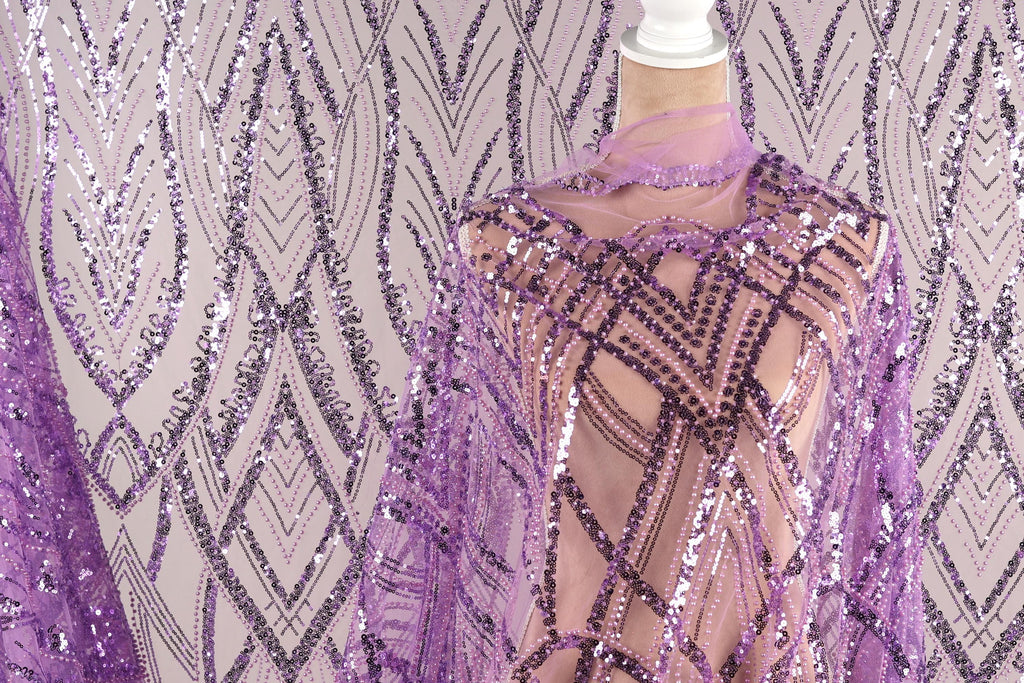 a mannequin wearing a purple sequin dress with a sheer overlay. The dress has a geometric pattern and appears to be made of sheer fabric.