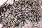 The image is a close-up view of a fabric with a floral pattern, featuring a variety of colorful flowers and leaves.