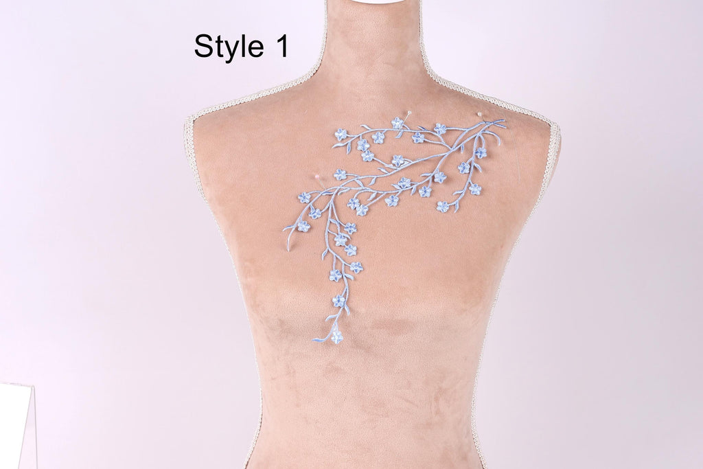 A mannequin with a delicate embroidered design on its back, featuring a floral pattern in shades of blue.