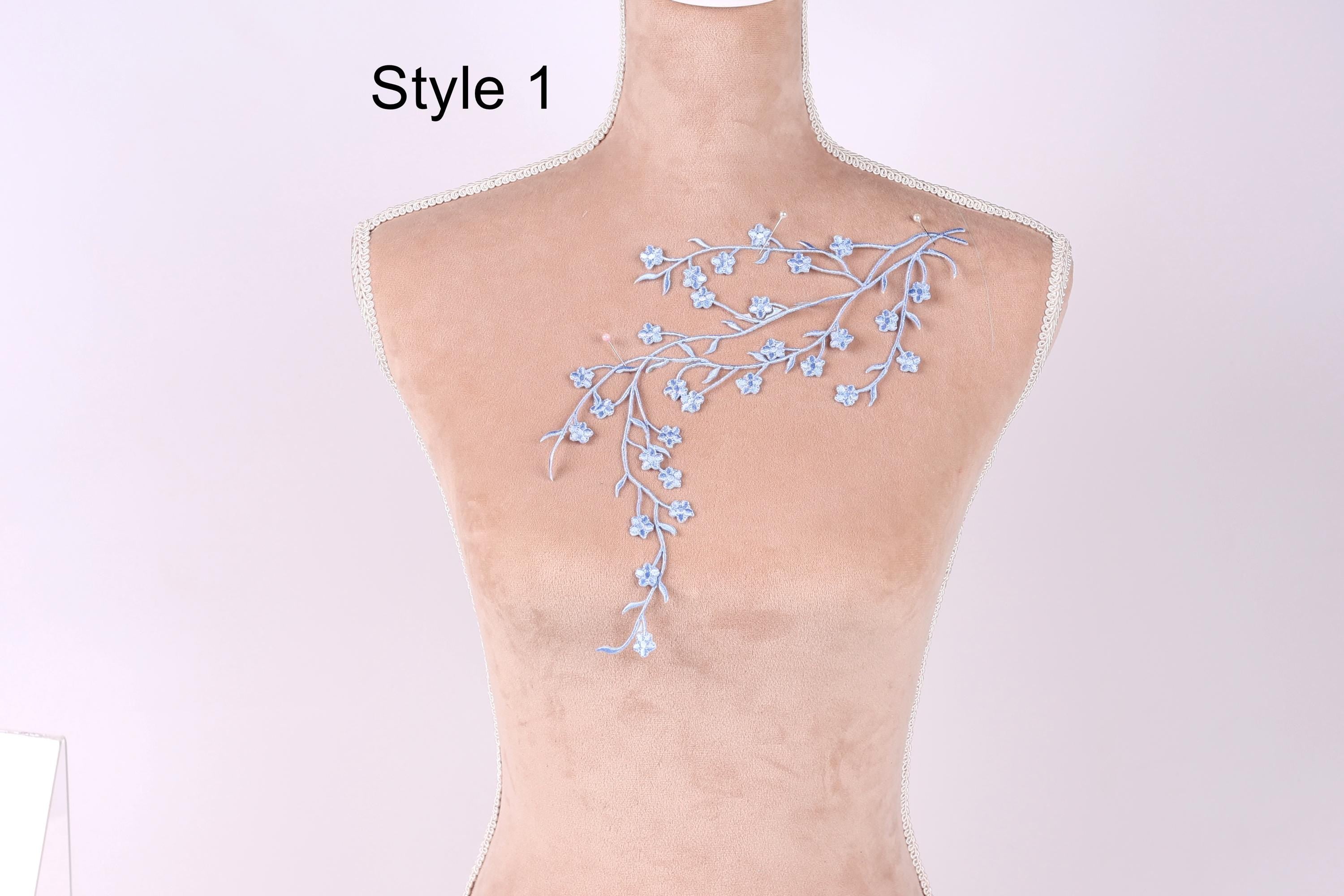 A mannequin with a delicate embroidered design on its back, featuring a floral pattern in shades of blue.