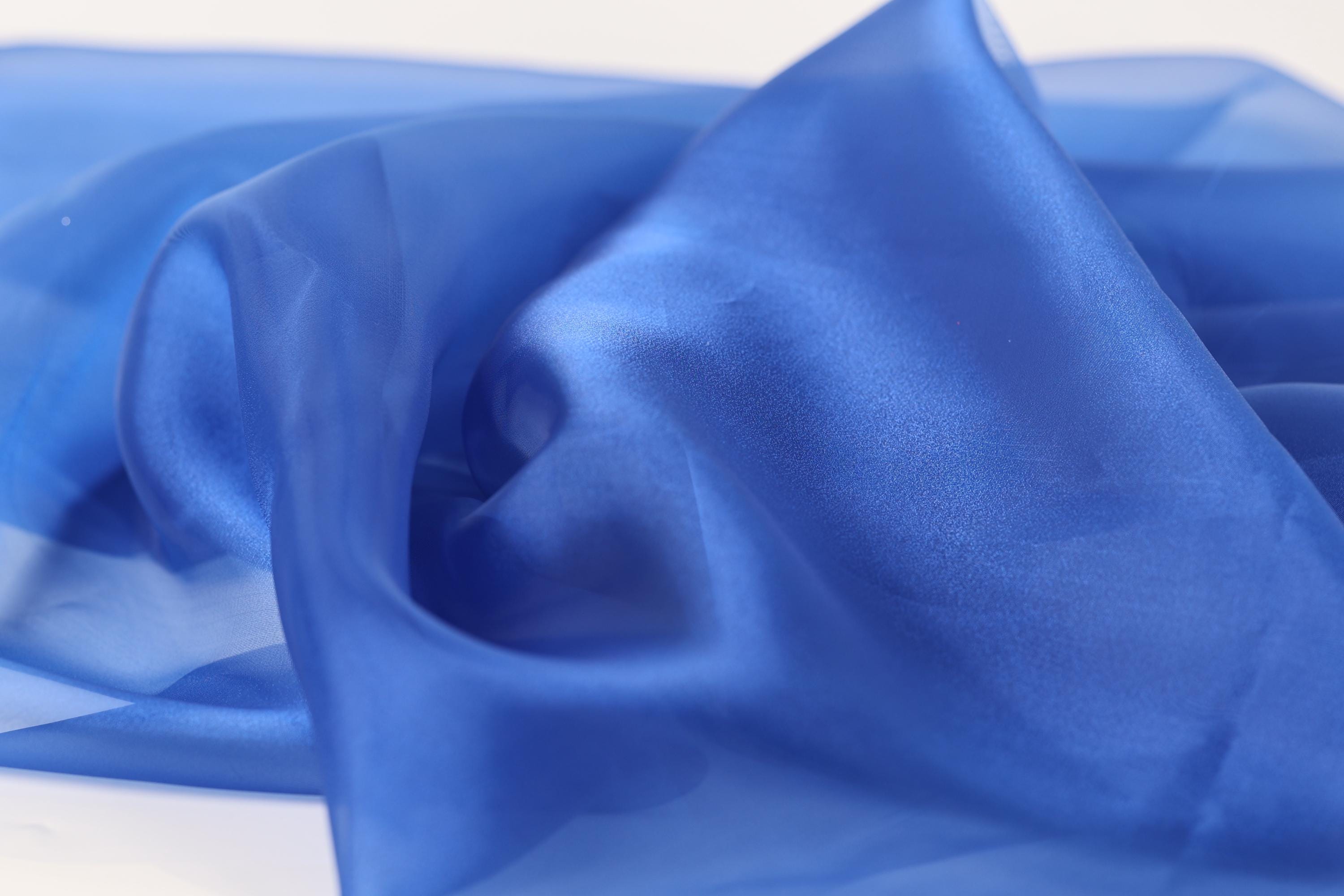 a close-up view of a blue fabric, possibly silk or chiffon, with a smooth and shiny texture.