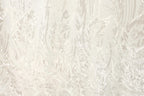 The image is a close-up of a fabric with a white and beige floral pattern, featuring a repeating design of leaves and branches.