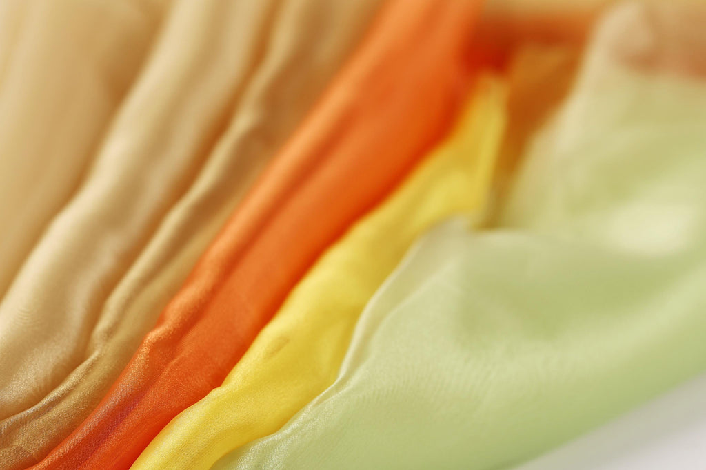 A close-up image of colorful fabric swatches, including yellow, orange, and green, arranged in a visually appealing manner.