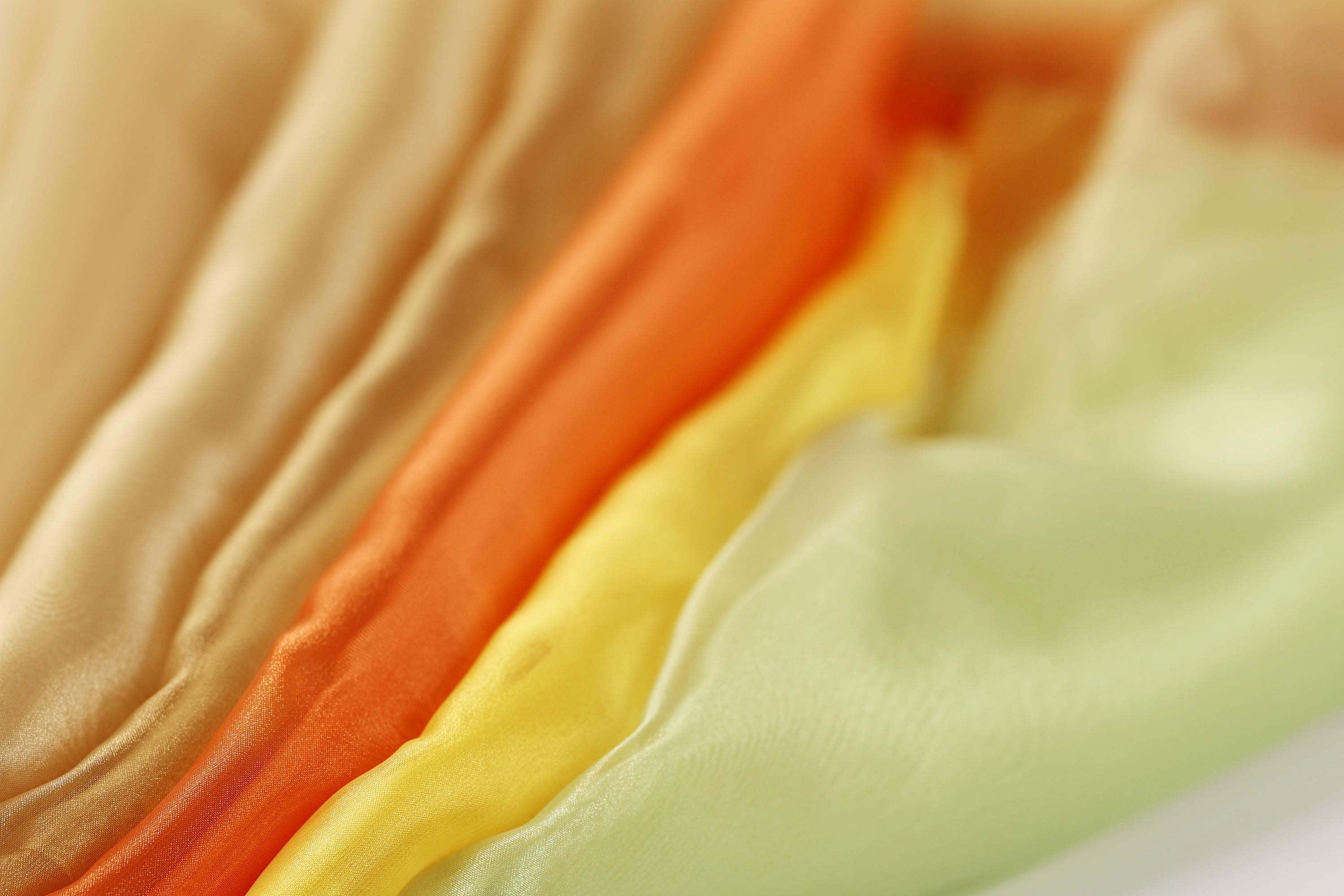A close-up image of colorful fabric swatches, including yellow, orange, and green, arranged in a visually appealing manner.