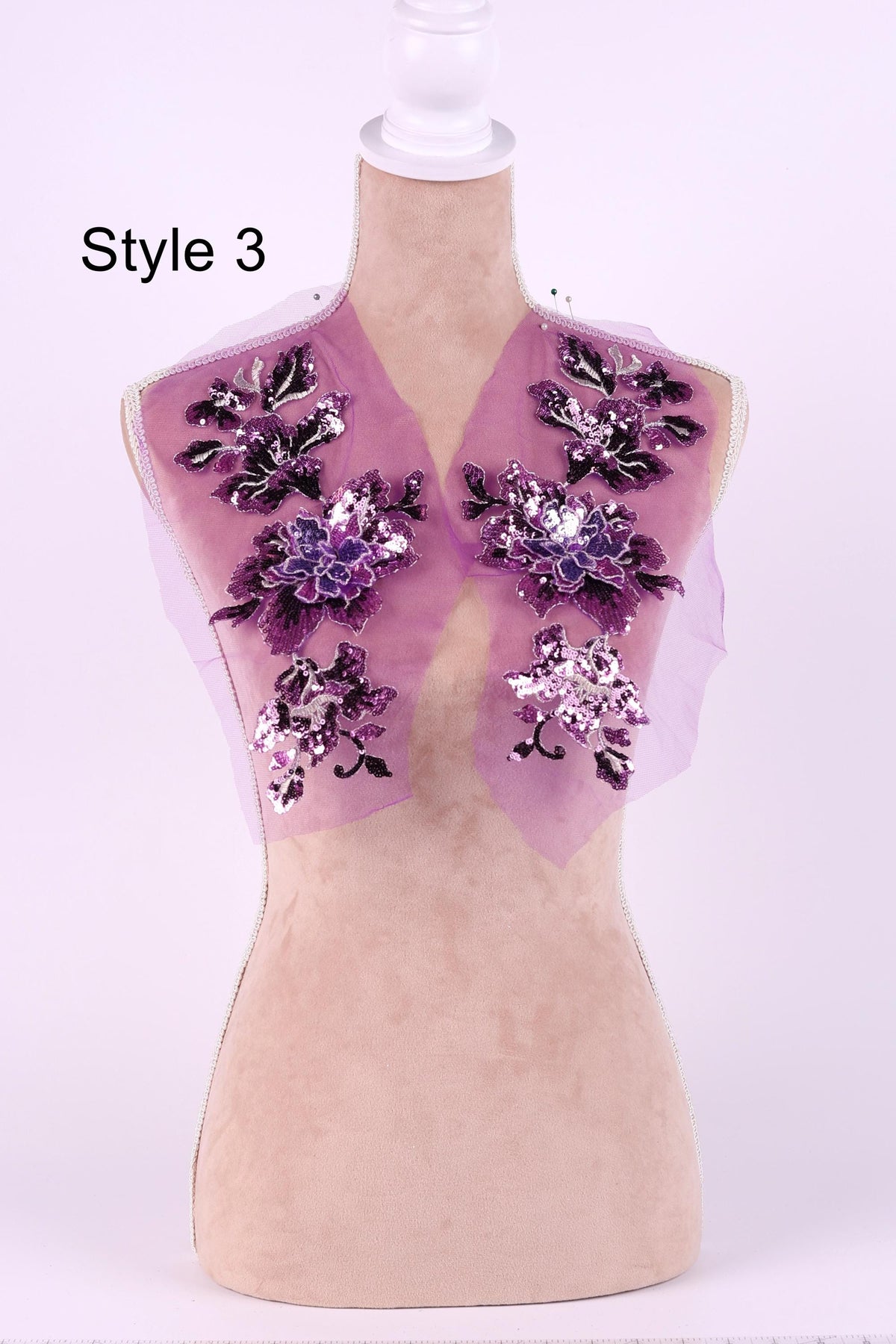 A mannequin with a pink fabric top and purple floral embellishments on the shoulders.