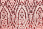 a close-up view of a fabric with a repeating pattern of red and black sequin designs. The pattern consists of various shapes and lines, creating a visually striking and intricate design.