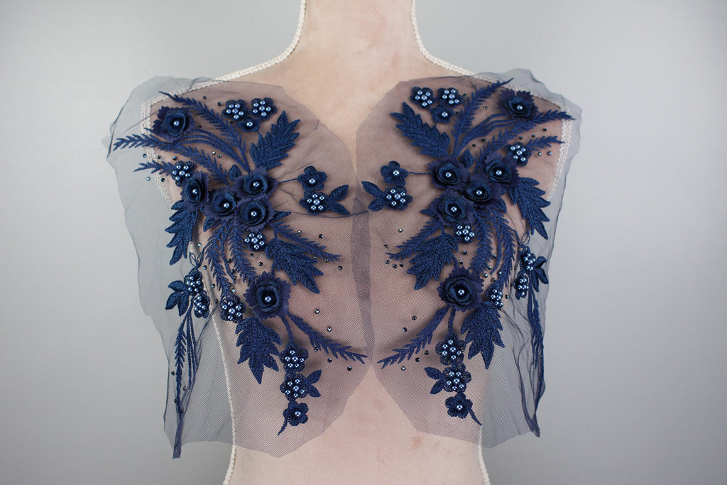 A mannequin wearing a dress with a blue floral pattern on the shoulders and back.