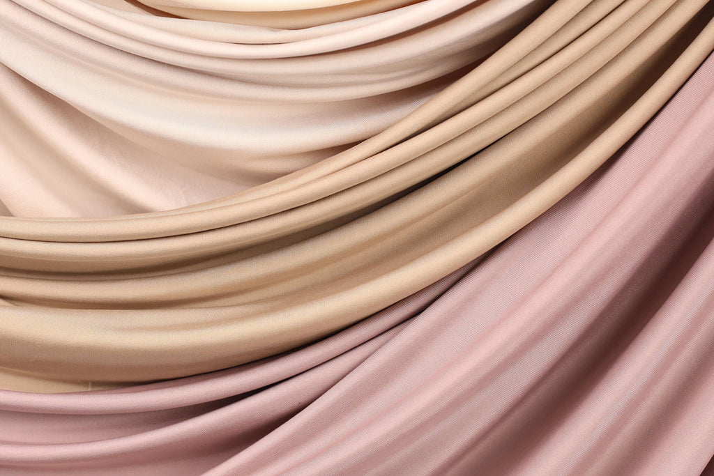 a close-up view of a fabric with a soft, flowing texture in shades of pink and beige.
