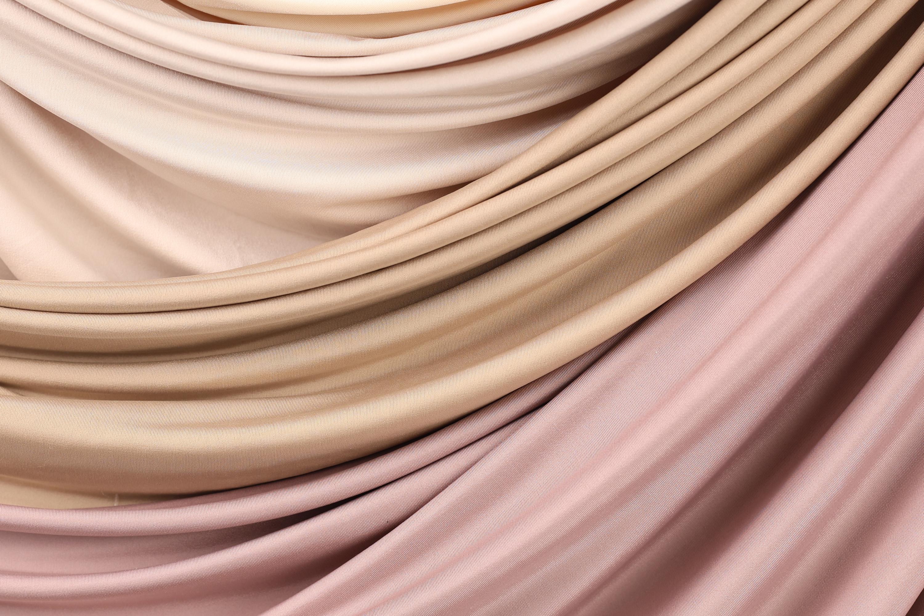 a close-up view of a fabric with a soft, flowing texture in shades of pink and beige.