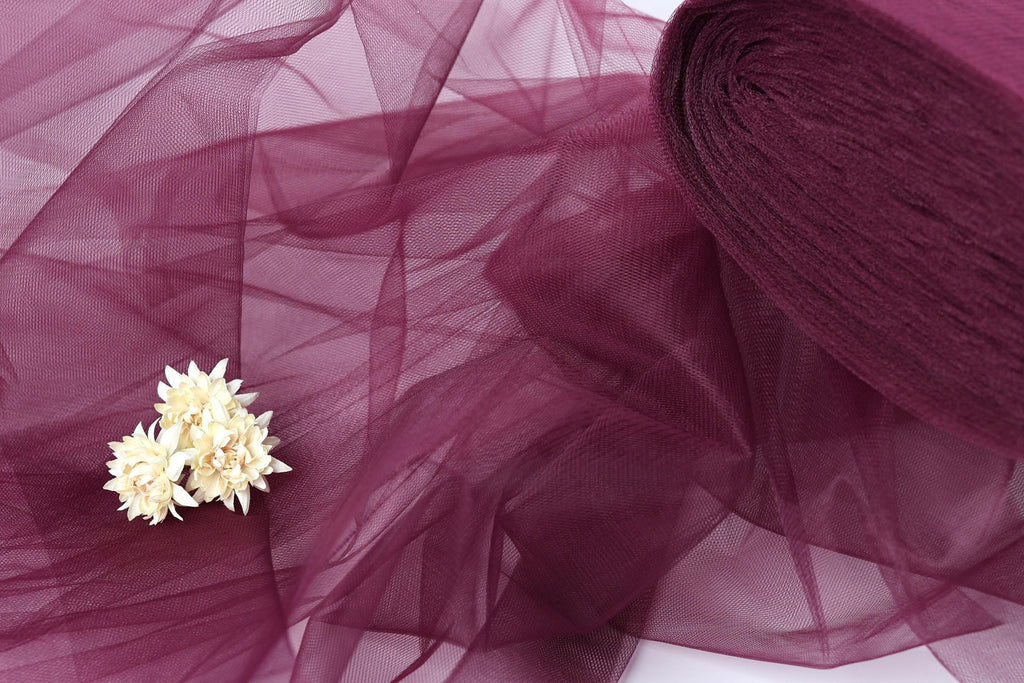 a close-up view of a delicate white flower resting on a soft, flowing purple tulle fabric.