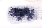 a close-up view of a piece of fabric with a floral design, including blue flowers and leaves. The fabric appears to be a lace or a similar type of material, and it is placed on a white surface. There is a ruler visible in the image, which is likely used for measuring or cutting the fabric.
