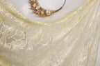 a close-up view of a delicate, yellow lace fabric with a floral pattern. The fabric appears to be made of sheer material, giving it a soft and flowing appearance. The lace is displayed against a plain white background, allowing the intricate details of the fabric to stand out.