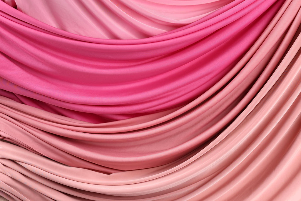 a close-up view of a fabric with a gradient of pink and peach colors, creating a visually appealing and textured appearance.