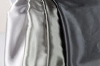 a close-up view of three different colored satin fabrics, with the first fabric being white, the second being silver, and the third being black.