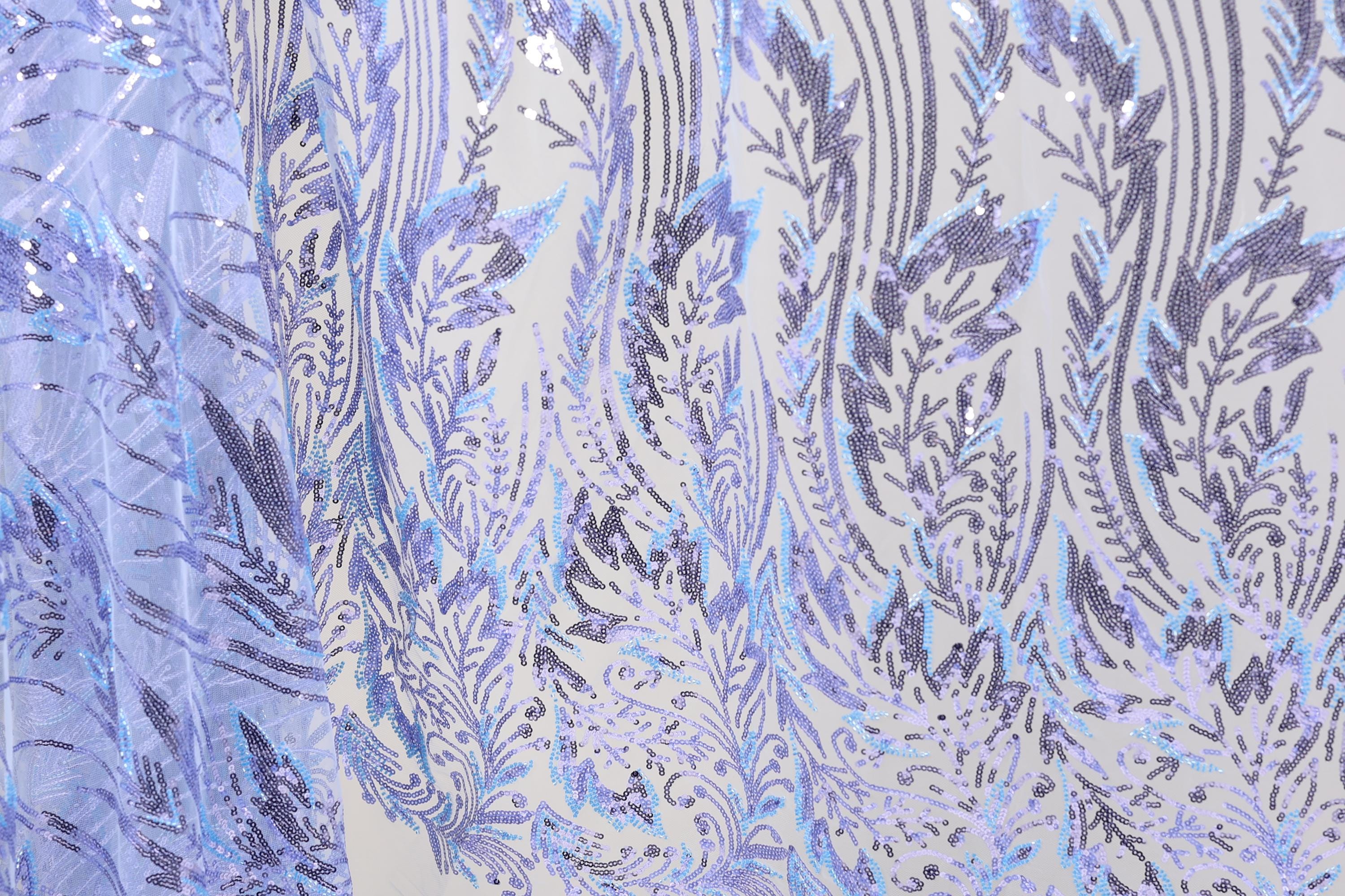 a close-up view of a fabric with a repeating pattern of purple and white sequin designs. The pattern appears to be a floral or leaf-like design, with the sequins adding a touch of sparkle and texture to the fabric. The fabric is predominantly white, with the purple and white sequins creating a visually striking contrast. The image does not contain any text or other discernible objects, and the focus is solely on the intricate and detailed pattern of the fabric.