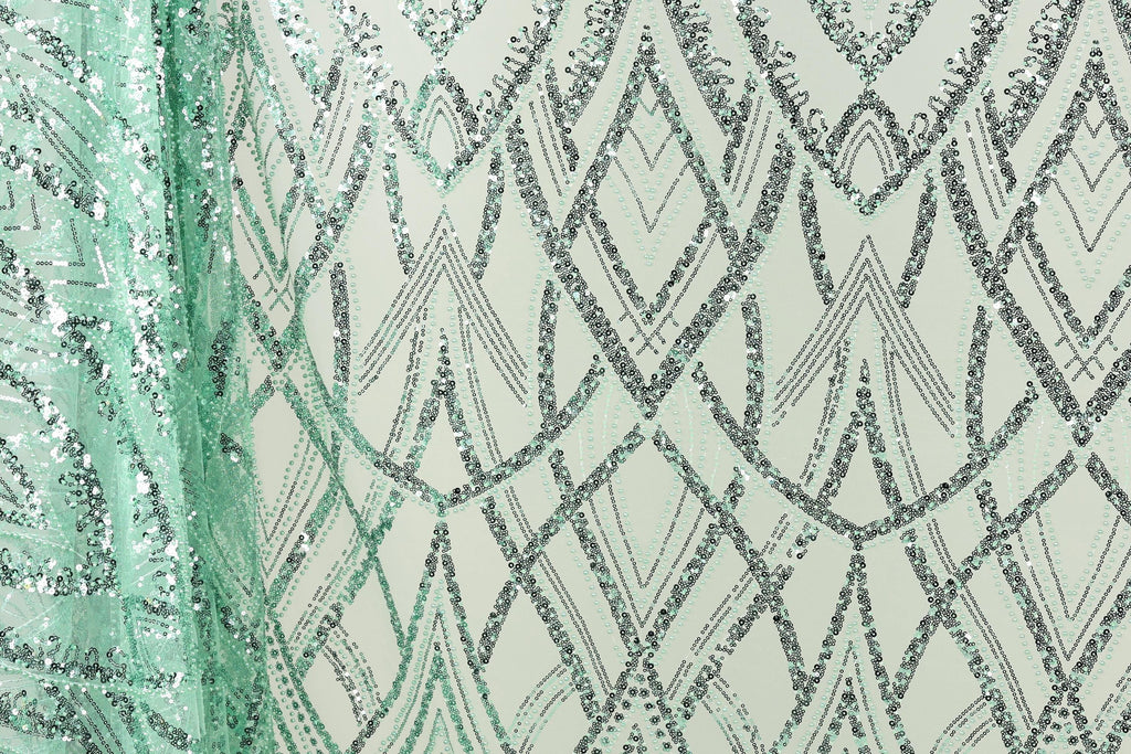 a close-up view of a fabric with a repeating pattern of diamond shapes in shades of green and silver, creating a visually striking and intricate design.