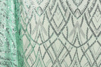 a close-up view of a fabric with a repeating pattern of diamond shapes in shades of green and silver, creating a visually striking and intricate design.