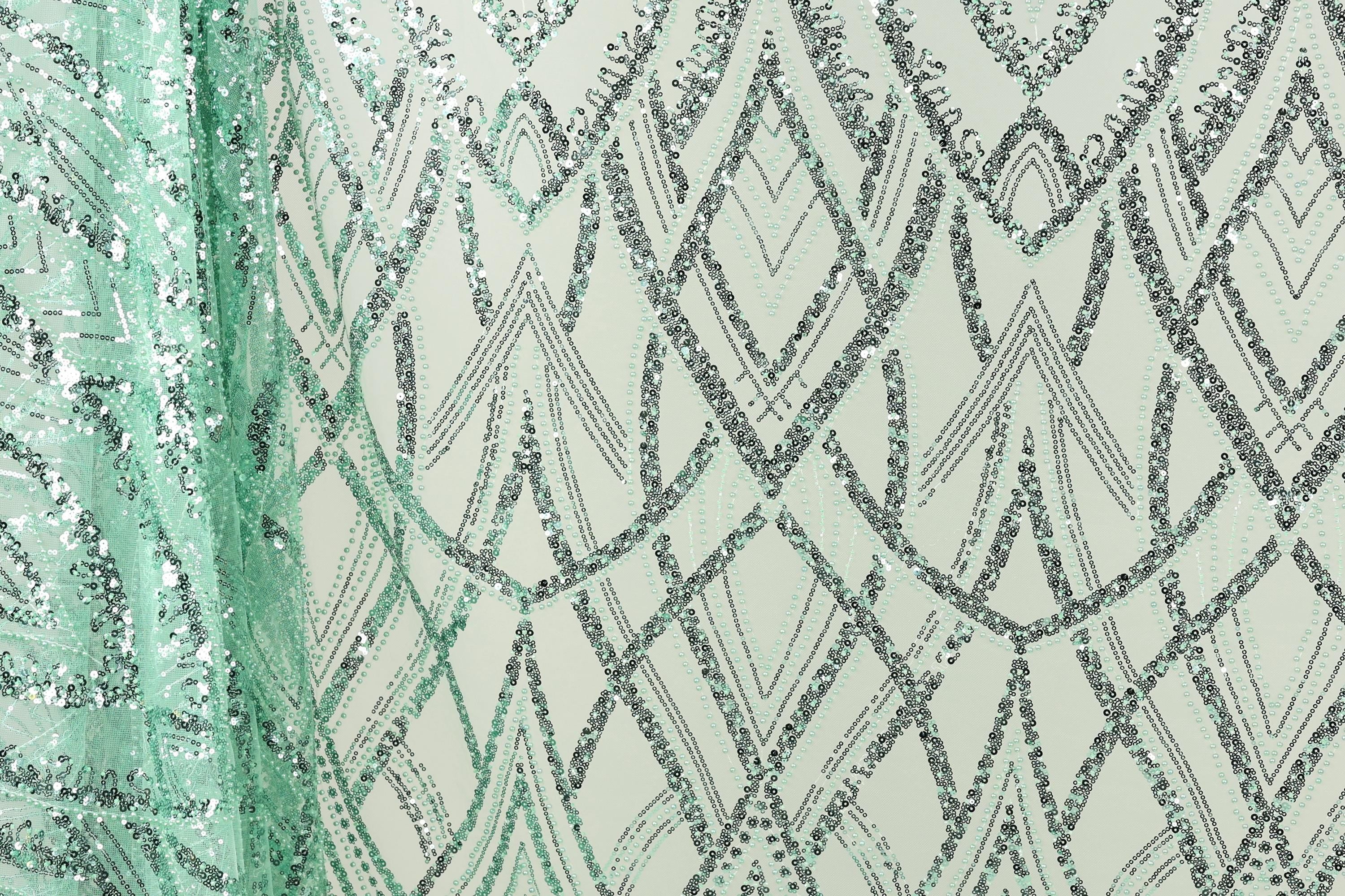 a close-up view of a fabric with a repeating pattern of diamond shapes in shades of green and silver, creating a visually striking and intricate design.