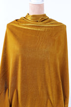 A mannequin wearing a gold velvet fabric draped over its body.