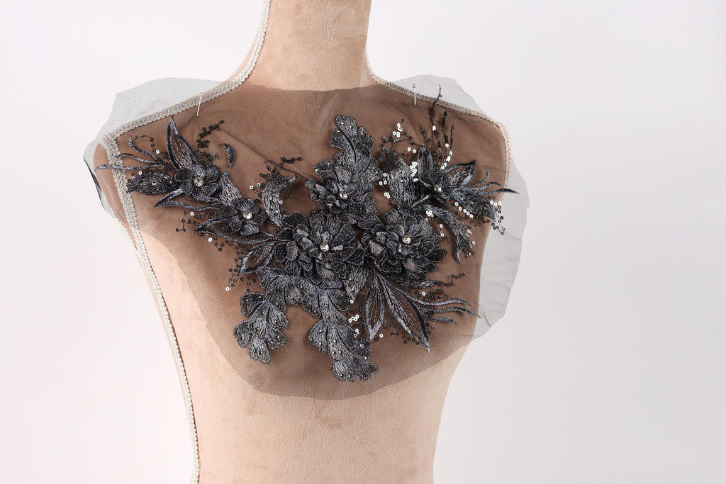 A mannequin with a decorative black lace or beaded floral pattern on its chest area.