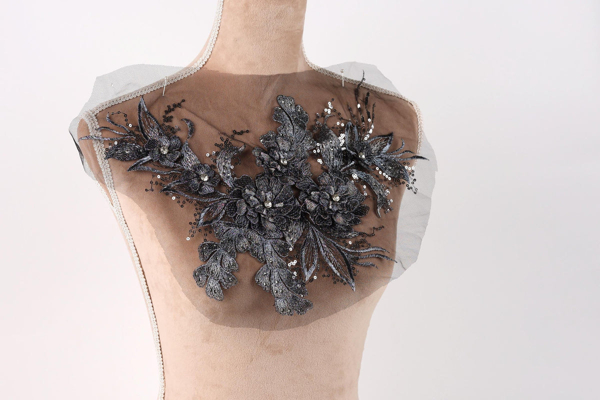 A mannequin with a decorative black lace or beaded floral pattern on its chest area.