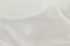 The image is a close-up of a white fabric, possibly silk or chiffon, with a soft, flowing texture.