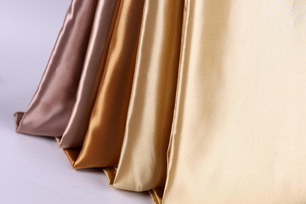 A close-up image of a fabric with a gradient of colors, including gold, brown, and beige.