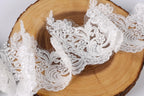 a close-up view of delicate white lace fabric, with intricate floral and lace patterns, resting on a wooden surface.