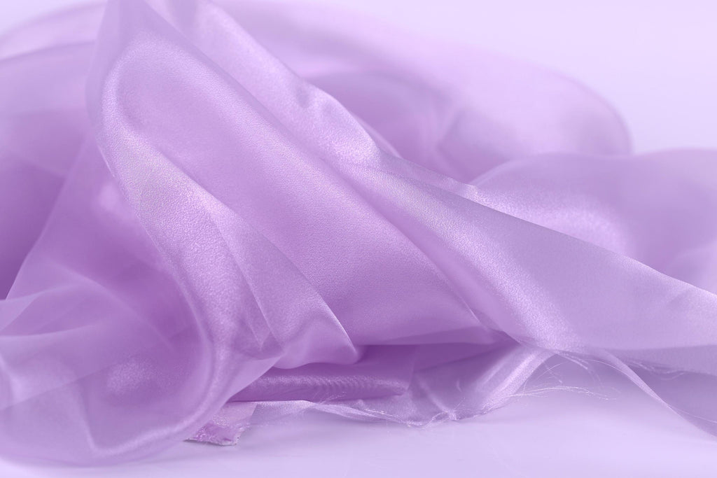 The image is a close-up of a soft, flowing fabric in a light purple color.