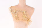 A mannequin torso with a beige fabric adorned with delicate gold floral embroidery.