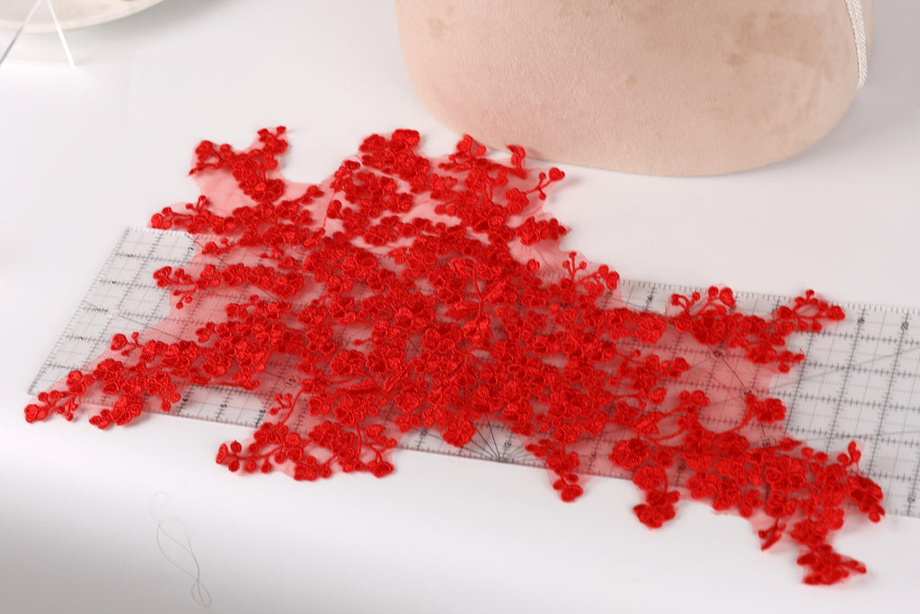 a collection of red lace flowers scattered on a white surface, with a ruler visible in the background.