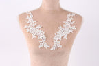 A mannequin wearing a white lace dress with delicate floral embroidery on the shoulders.