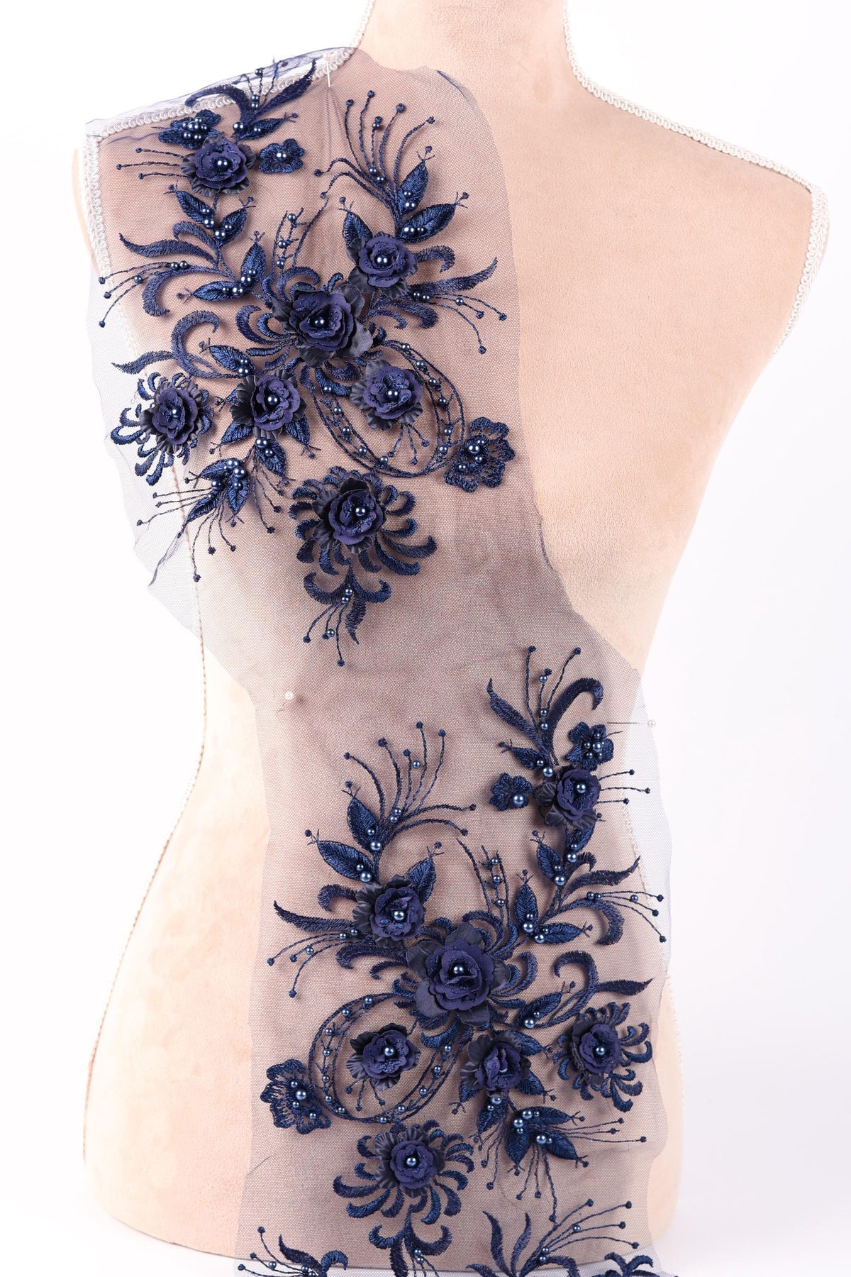 a close-up view of a delicate, intricate piece of lace or fabric adorned with a floral pattern in shades of blue. The design is detailed and ornate, showcasing the craftsmanship and artistry involved in creating such a piece.