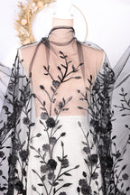 a dress with a black floral pattern on the bodice and sheer fabric with black floral designs.