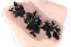 a close-up view of a delicate black lace flower embroidery on a light-colored fabric.