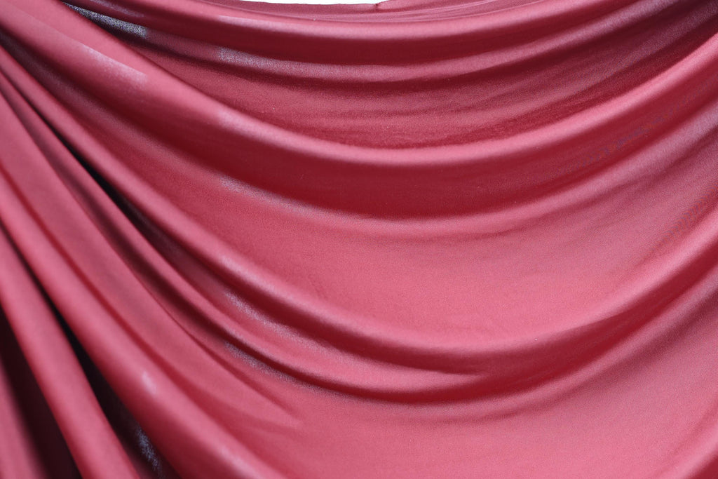 a close-up view of a red fabric, possibly silk or chiffon, with a smooth, flowing texture.