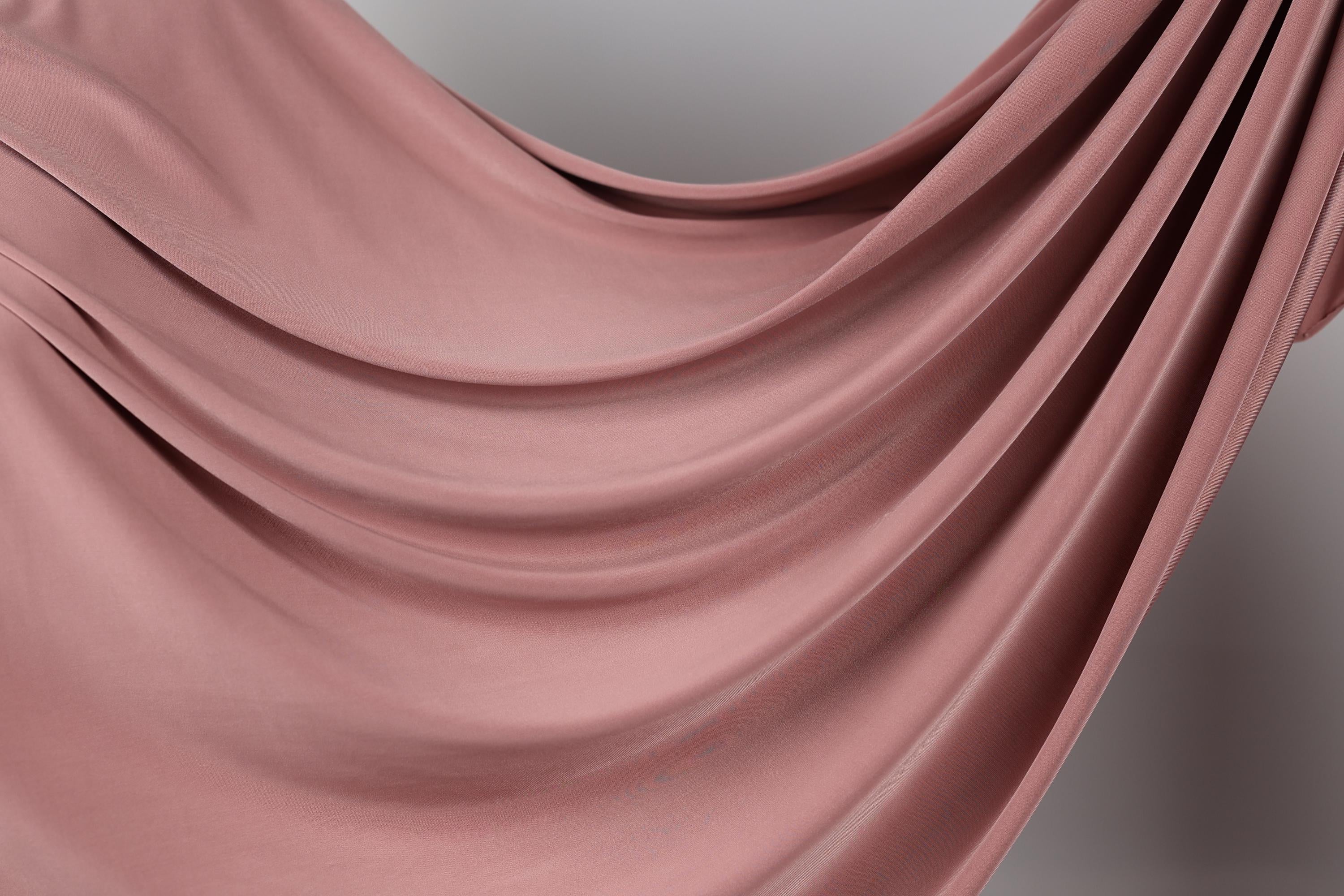 A close-up view of a flowing, pink fabric, possibly a sheer or sheer-like material, with a soft, draped appearance.
