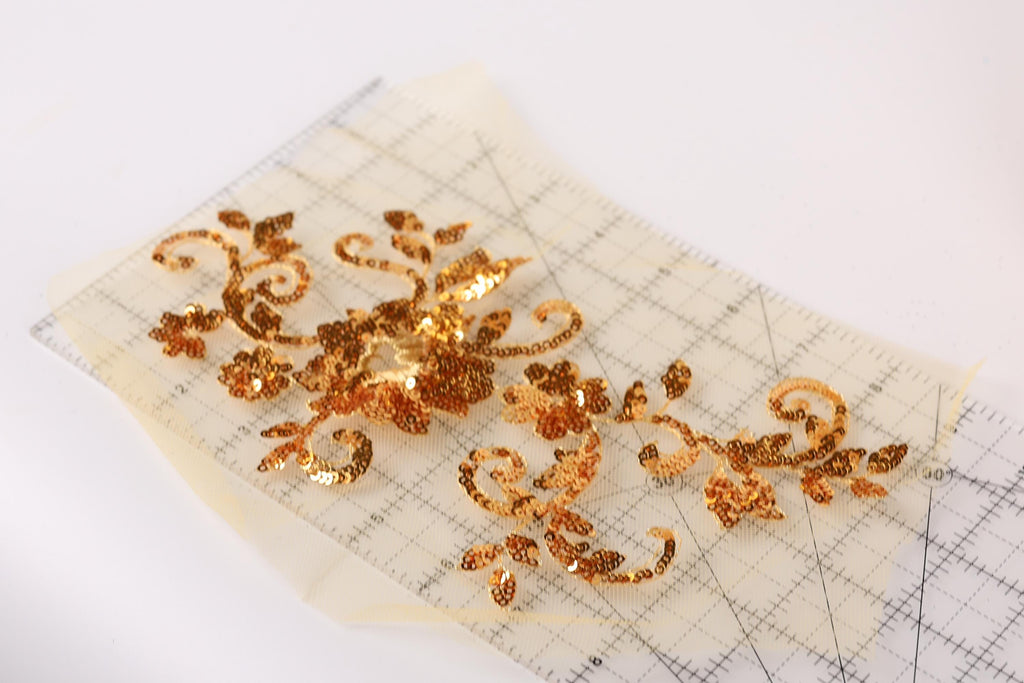 a piece of paper with a decorative gold sequin design on it, placed on a white surface.