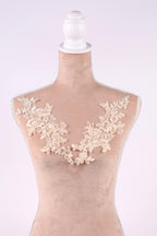 A mannequin with a beige body and a white headpiece, adorned with delicate white lace flowers on the bust area.