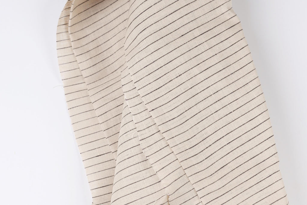 A close-up view of a fabric with horizontal black stripes on a beige background.