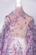 a mannequin wearing a sheer, purple, and pink sequined fabric draped over it.