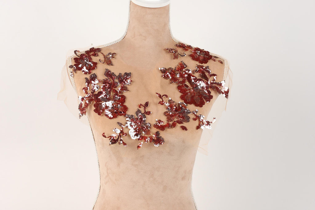A mannequin with a beige body and red sequin flowers on its shoulders.