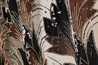 The image is a close-up of a fabric with a floral pattern, featuring a mix of black, brown, and gold colors. The fabric appears to be made of a shiny material, possibly sequin or glitter, and has a textured appearance.