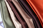 A close-up view of a collection of colorful fabric swatches, including shades of green, brown, and orange.