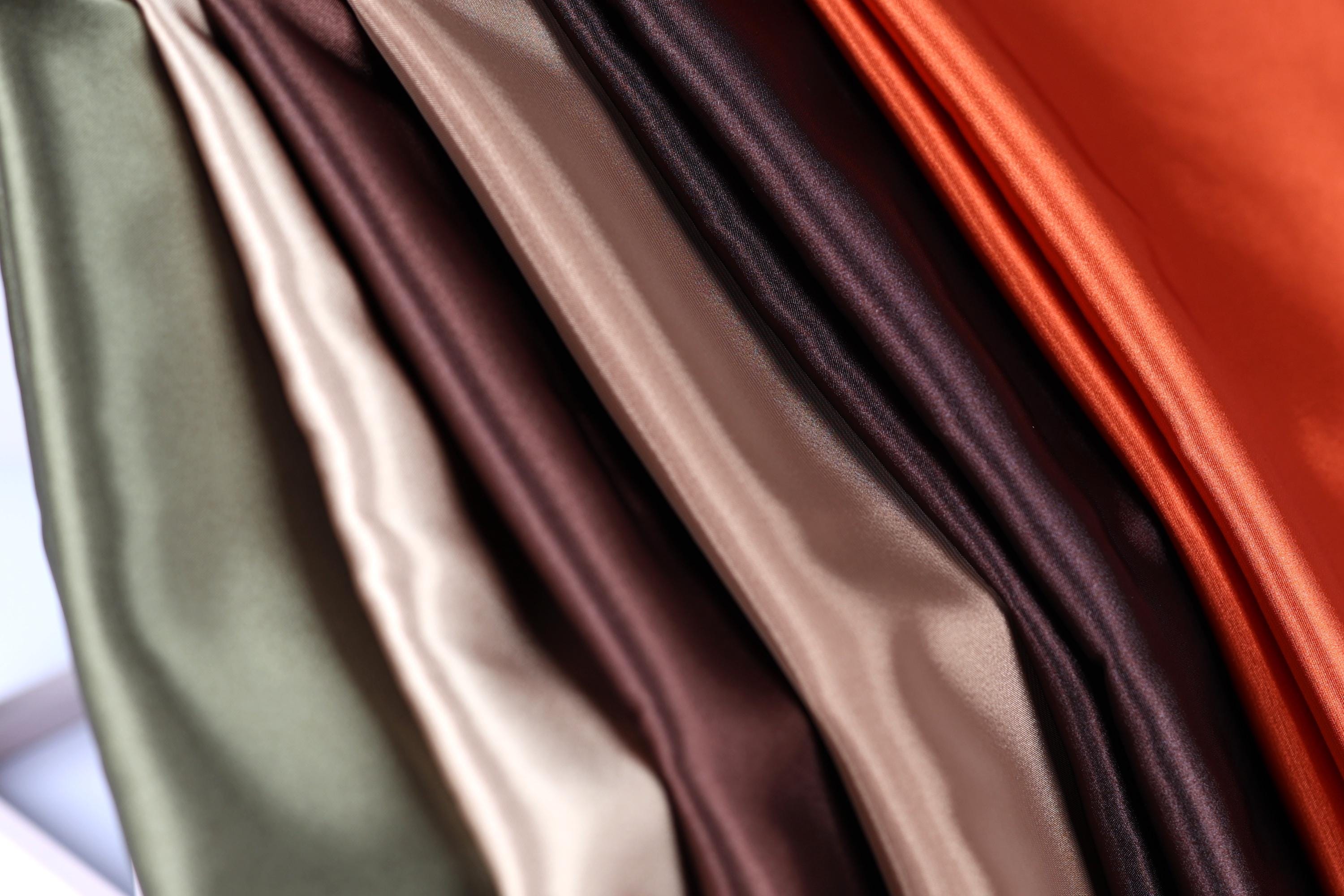 A close-up view of a collection of colorful fabric swatches, including shades of green, brown, and orange.