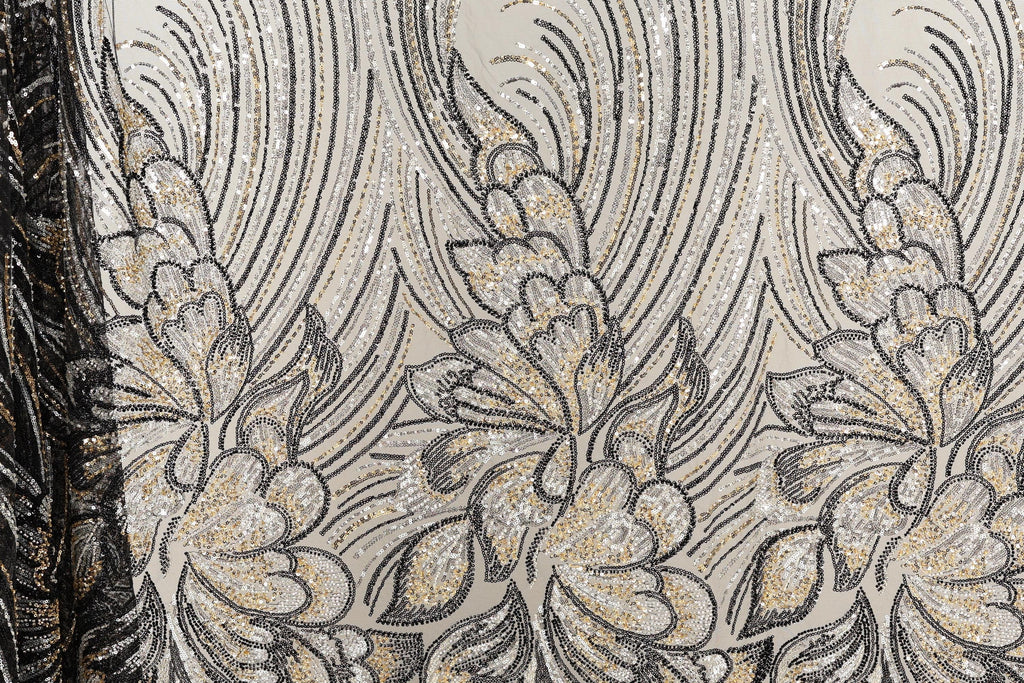 a close-up view of a fabric with a floral pattern. The fabric appears to be made of sequin material, with a repeating pattern of black and gold flowers and leaves. The pattern is intricate and detailed, showcasing the craftsmanship and artistry involved in creating the fabric.