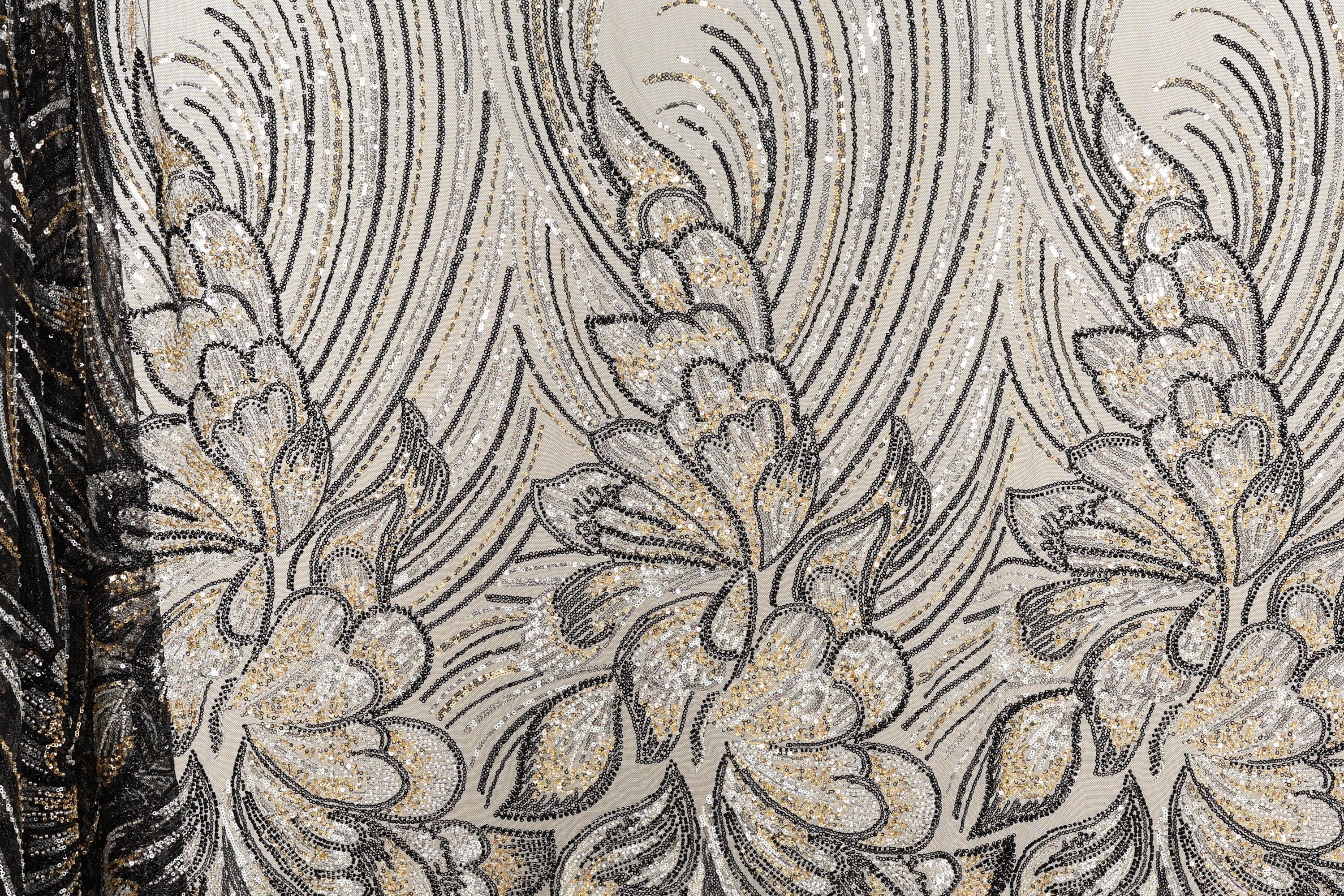 a close-up view of a fabric with a floral pattern. The fabric appears to be made of sequin material, with a repeating pattern of black and gold flowers and leaves. The pattern is intricate and detailed, showcasing the craftsmanship and artistry involved in creating the fabric.